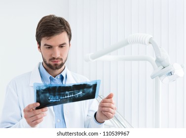 Dentist carefully examines the roentgenogram, white background.
