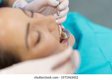 Dentist checking the inside of her patient's teeth with a dental mirror.