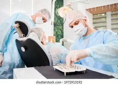 Dentist choosing dental implants while man colleague examining patient teeth. Doctor sitting at the table with dental implant kit. Concept of dentistry and implant placement.