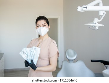 The Dentist In The Clinic Holds A Toothpick In His Hands. Nurse In Respirator With In Dental Office With Tools