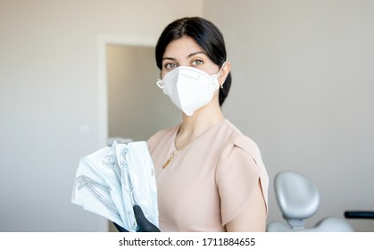 The Dentist In The Clinic Holds A Toothpick In His Hands. Nurse In Respirator With In Dental Office With Tools