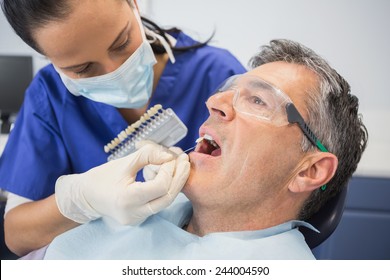 Dentist comparing teeth whitening of her patient in dental clinic