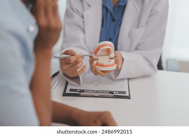 Dentist consultation - patient visit at the dental clinic office. Female dentist wearing dentures to explain teeth Recommend guidelines for orthodontics Dentist giving advice on patient's condition - Powered by Shutterstock