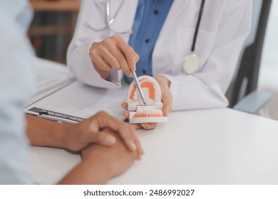 Dentist consultation - patient visit at the dental clinic office. Female dentist wearing dentures to explain teeth Recommend guidelines for orthodontics Dentist giving advice on patient's condition - Powered by Shutterstock