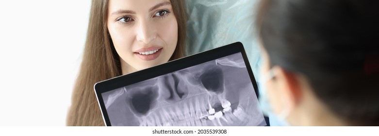 Dentist doctor holding digital tablet with teeth xray in front of patient - Powered by Shutterstock