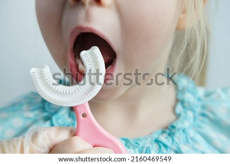 dentist, doctor teaches child, small patient to silicone brush capa his teeth, closeup kid's teeth, concept pediatric dentistry, dental treatment, correction of occlusion, oral care, caries prevention