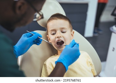 Dentist doing regular dental check-up to little boy. Little cute smiling boy is sitting in dental chair in clinic, office. Doctor is preparing for examination of child teeth with tools.  - Shutterstock ID 2195768761
