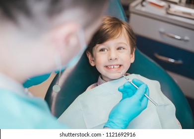 Dentist examining  boy's teeth in clinic. A small patient in the dental chair smiles. Dantist treats teeth

