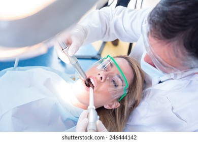 Dentist Examining His Patient With A Suction Hose At The Dental Clinic