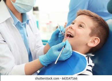 Dentist examining little boy's teeth in clinic - Powered by Shutterstock