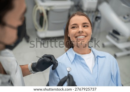 Dentist examining patient teeth using mouth mirror and dental probe in clinic