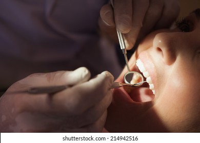 Dentist examining a patients teeth in the dentists chair under bright light at the dental clinic - Powered by Shutterstock