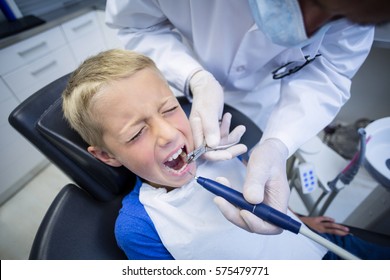Dentist examining a young patient with tools at dental clinic - Shutterstock ID 575479771