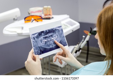 Dentist explaining the details of a x-ray teeth picture to his patient in clinic