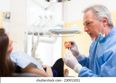 Dentist Explaining A Treatment Using A Model