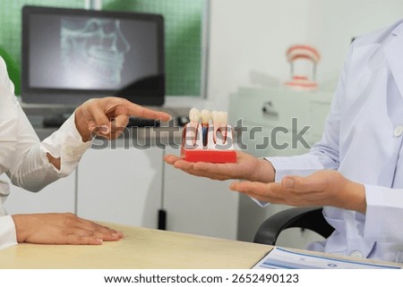 Dentist explains dental implants using model in clinic
