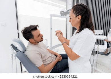 Dentist explains dental procedures to patient in modern clinic during a routine check-up - Powered by Shutterstock