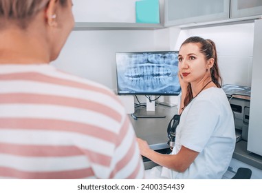 Dentist female doctor in uniform showing intraoral 3D dental X-rays scan to patient on PC screen. Dental clinic patient visit modern medical ward. Health teeth care, medicare industry and technology. - Powered by Shutterstock