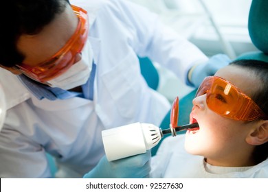 Dentist Fixing A Cavity On A Boy Using The Laser Light