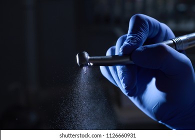 Dentist hand with drill illustrates the operation of the dentist dental drill machine with water. Dentist's hands with blue gloves working with dental drill in dental office. Close up, selective focus - Shutterstock ID 1126660931