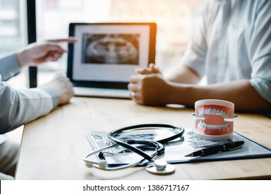 Dentist Hand Pointing X-ray Picture In Laptop Computer And Talking To The Patient About Medication And Surgery Treatment.