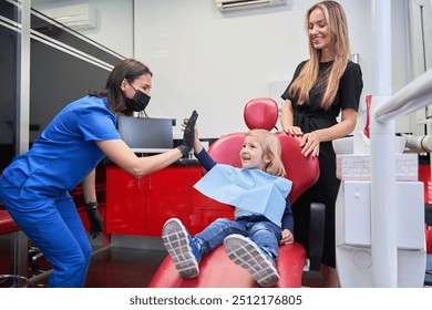 dentist high-fiving the child who has come to the dentist with his mother - Powered by Shutterstock