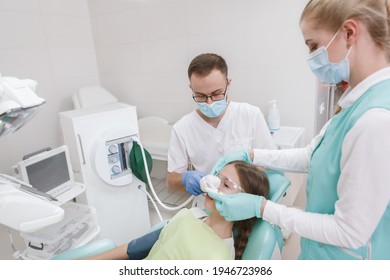 Dentist and his assistant using inhalation sedation on young girl before dental treatment - Shutterstock ID 1946723986