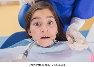 Dentist and his dental assistant examining a terrified young patient in dental clinic - Powered by Shutterstock