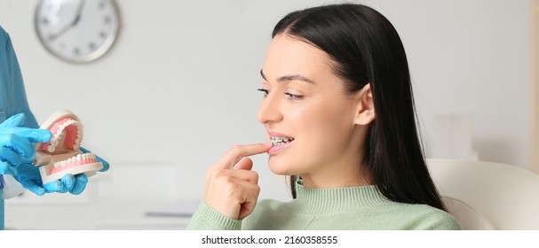 Dentist Holding Model Of Jaw And Woman With Dental Braces In Clinic