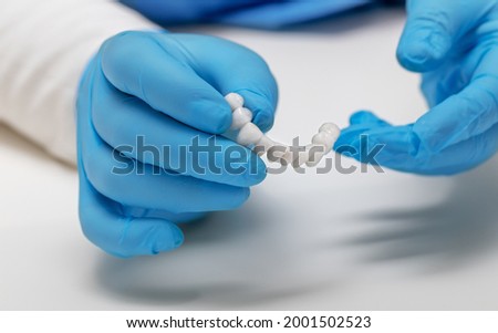 dentist holds ceramic dental crowns in his hands, zirconium bridge, close-up