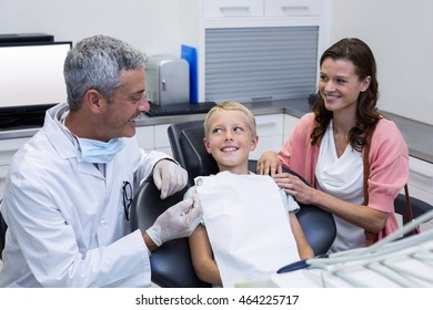 Dentist interacting with mother and son while dental examination at dental clinic