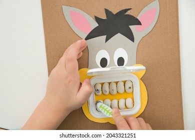 A dentist. Kid plays with DIY toy. Boy washing donkey teeth with toothbrush. Idea for smart mommy how to motivate children to brush your teeth? Wet wipes door mouth and bean teeth.