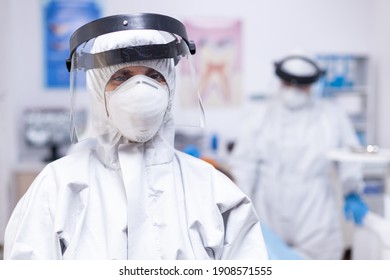 Dentist Looking Exhausted At Camera Dressed In Coverall In The Course Of Covid-19 Pandemic. Portrait Of Tired Stomatologist Wearing Coronavirus Ppe Suit Looking At Camera.