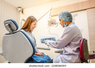 The dentist is looking at the patient's dental x-ray results for an effective treatment and improves the patient's dental health and a bright smile. - Shutterstock ID 2248584393
