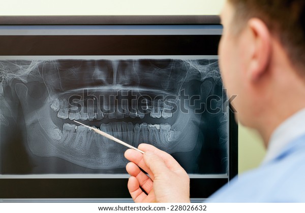 Dentist\
looking teeth on digital X-Ray computer\
monitor