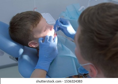 Dentist Making Fluoridation Of Child Boy Teeth After Cleaning For Protection. Doctor Hygienist Applying Fluoride To Teen Teeth With Brush. Covering Teeth With Fluoride Gel In Dentistry. Cure Concept.