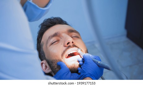 Dentist In Medical Mask Curing Teeth Of Patient With Dental Drill, Blurred Foreground