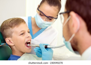 Dentist and nurse are curing a little boy patient.