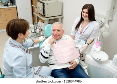 Dentist And Nurse Making Professional Teeth Checkup Male Senior Patient At The Dental Office. Dental Care For Older People. Dentistry, Medicine And Health Care Concept