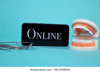 Dentist Online Appointment. Phone With Medical Instruments And Jaw Isolated On The Blue Background.