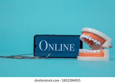 Dentist Online Appointment. Phone With Medical Instruments And Jaw Isolated On The Blue Background.