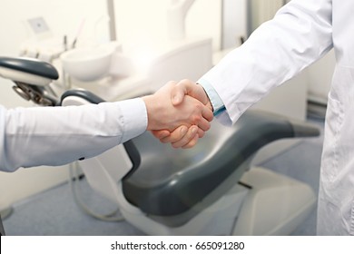A dentist and a patient are handshaking. Invitation to the dental clinic concept - Powered by Shutterstock