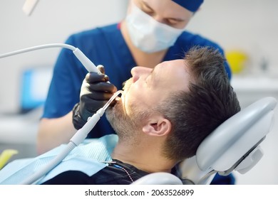 Dentist and patient at medical center. Doctor treats a mature man teeth with dental drill. Orthodontist and prosthetics appointment. Hygiene and teeth healthy.
