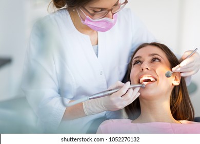 Dentist and patient in dentist office - Shutterstock ID 1052270132