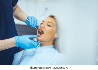 Dentist And Patient In Dentist Office. Over The Shoulder View Of A Dentist Examining A Patients Teeth In Dental Clinic. Female Having Her Teeth Examined By A Dentist.