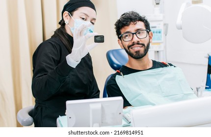 Dentist with patient showing him a periapical x-ray, View of dentist with patient reviewing dental x-ray. Dentist showing periapical x-ray to patient - Powered by Shutterstock
