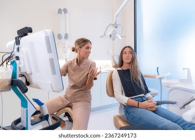 Dentist and patient talking about treatment in a clinic while looking at a screen - Shutterstock ID 2367249173
