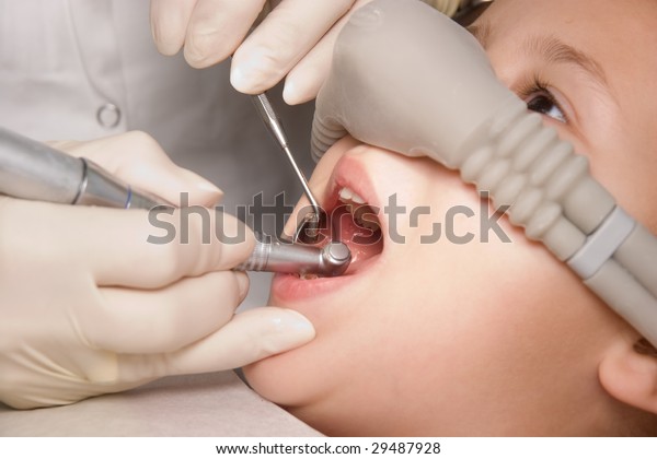 dentist performs a procedure of care for teeth of child