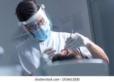 Dentist performs a regular examination of the patient - Shutterstock ID 1924611830