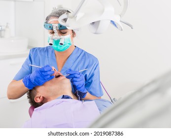 Dentist Professional Filling Teeth For Man Patient Sitting In Medical Chair